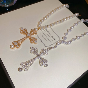 Detail of hollow cross pendants with pearls and rhinestones on gold and silver chains