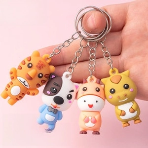 Detailed view of four assorted PVC cartoon animal keychains held in hand for scale