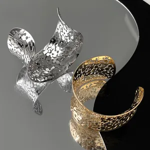 Macro detail of textured gold and silver open bangles with irregular hammered finish