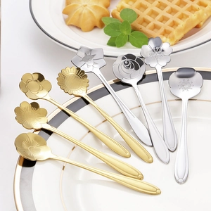 Set of 8 stainless steel flower shaped coffee spoons in gold and silver on white plate