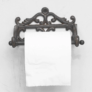 Porte-essuie-tout rétro en fonte avec motifs décoratifs sur un mur texturé