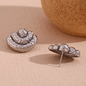 Detailed close-up of silver-tone hammered metal earrings with layered semi-circle design