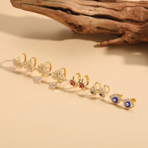 Golden Evil Eye earring set with zircon and gemstones on a minimalist beige backdrop