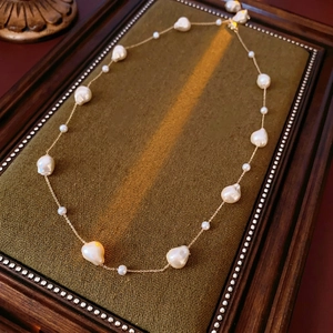 Baroque pearl necklace with gold-plated chain on vintage velvet display tray