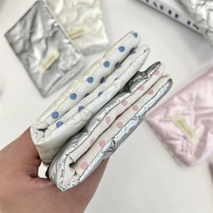 Close-up of metallic quilted passport holder with bow detail and polka dot lining