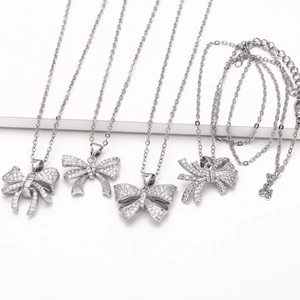 Minimalist silver bow necklaces with sparkling cubic zirconia on a white background