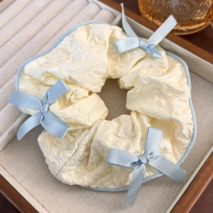 Detail of beige seersucker scrunchie with blue lace trim and bows in a jewelry box