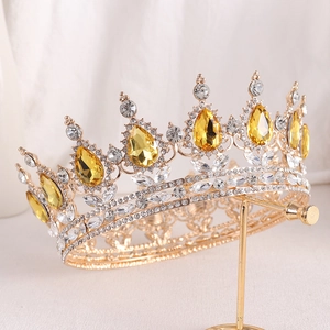 Close-up of golden bridal crown with pear-cut yellow rhinestones on display stand