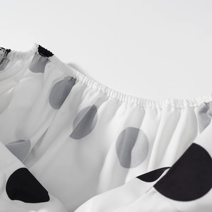 Détail de l'encolure élastique d'un haut blanc à pois noirs et gris en mousseline légère