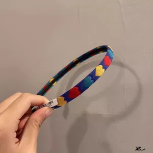 Détail d'un serre-tête en tricot bleu marine avec broderies de cœurs et texture tissée