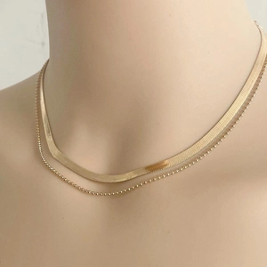 Detail of layered gold snake bone chain and bead necklace on a mannequin