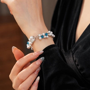 Dettaglio di un bracciale vintage con gemme blu e perle bianche indossato sul polso