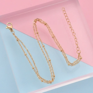 Detail of gold double-layer bead chain with lobster clasp and extension on acrylic stand