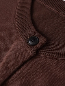 Close-up of the fine ribbed crew neck and matte button on this brown knit cardigan