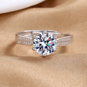 Elegant six-prong 2-carat sparkling ring with side-stone band on golden satin fabric