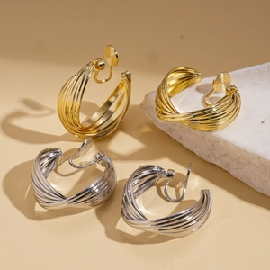Textured gold and silver twisted hoop clip-on earrings displayed on a white stone
