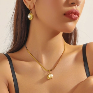 Close-up of gold-plated heart fan necklace and pearl earrings on a female model