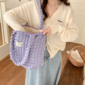 Detail of purple bubble texture shoulder bag with 3D floral pattern on a cozy model