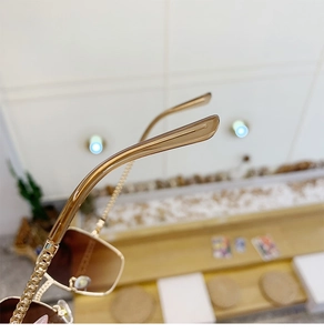Detailopname van de gouden kettingpoten op een vintage zonnebril met kleurverloop