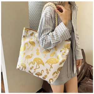 Detailed view of white canvas tote bag with gold flamingo and pineapple prints and rope handle
