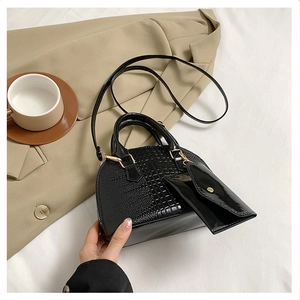 Detail of black crocodile texture shell bag with gold hardware and small hanging pouch