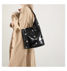 Detail of glossy black hobo shoulder bag featuring stylish silver metal rivets