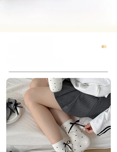 Detail of white cotton mid-calf socks with black polka dots and ribbon bow decoration