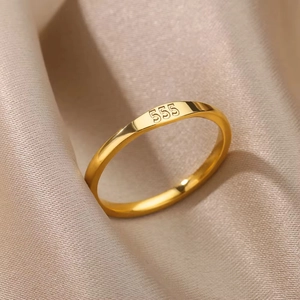 Detailed macro view of gold plated titanium ring featuring engraved number 555 on polished surface