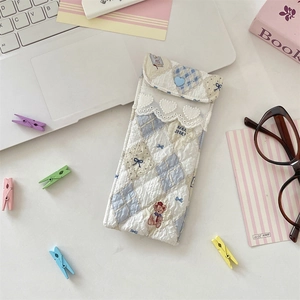 Close-up of quilted bear pattern glasses pouch with heart button on a study desk