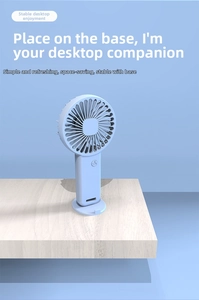 Detail view of the portable blue mini fan with its detachable round base on a wooden desk