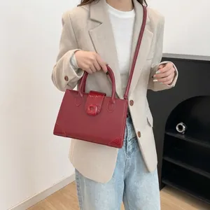 Red crocodile texture shoulder bag with round clasp and crossbody strap for women