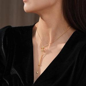 Detail of a gold-plated necklace with a zircon spiral pendant and heart on a model
