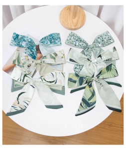 Detailed flat lay of five assorted green floral silk ribbons on a white surface