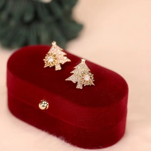 Close-up of golden Christmas tree studs with sparkling zircons on red velvet box
