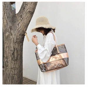 Clear PVC tote bag with rose gold pouch held by a model in a breezy beach outfit