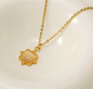 Detail of 18K gold stainless steel necklace with square sun pendant and brown natural stone