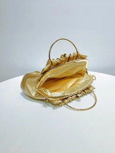 Detail view of the golden evening bag interior with metal ring handle and satin lining