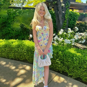 Floral maxi dress with pleated bodice and asymmetrical ruffled hem in garden setting