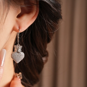 Gros plan d'une boucle d'oreille cœur et couronne en argent avec zircons sur un mannequin