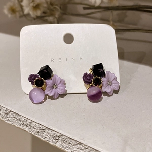 Macro detail of purple flower earrings with faux crystal beads and dark geometric charms