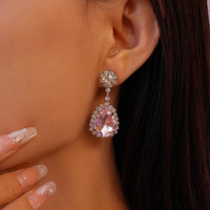 Gros plan d'une boucle d'oreille goutte rose avec halo de diamants sur un mannequin