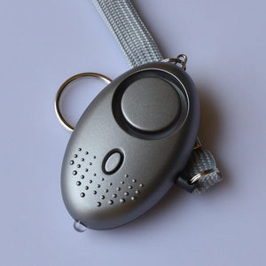 Detail view of a matte grey personal security alarm with a hand strap and LED flashlight