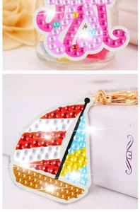 Detailed macro of crystal diamond painting keychains in pink and sailboat shapes
