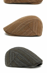 Detail showing herringbone tweed texture on three stacked vintage flat caps for autumn