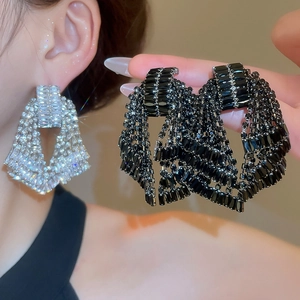Close-up of sparkling rhinestone bow tassel earrings in silver and black color options