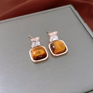 Gros plan de boucles d'oreilles œil de tigre plaquées or 18 carats avec zircons