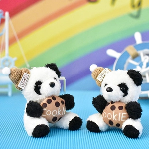 Detailopname van schattige pluche panda sleutelhangers met gebreide mutsen en koekjes