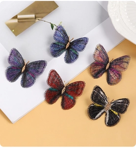 Détail de cinq broches papillon brodées en dégradé de couleurs vives sur fond bicolore