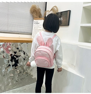 Pink sequin backpack for kids featuring cute rabbit ears and fluffy white pompom charm