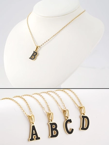 Detalle de collar letra B de acero de titanio dorado con esmalte negro en modelo